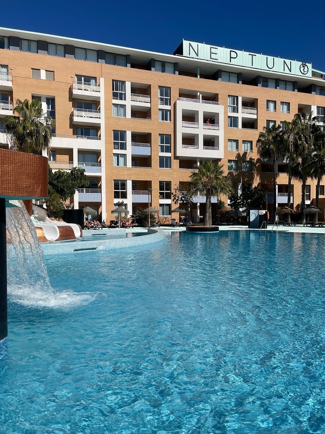 una piscina frente a un edificio con la palabra neptuno en la parte superior
