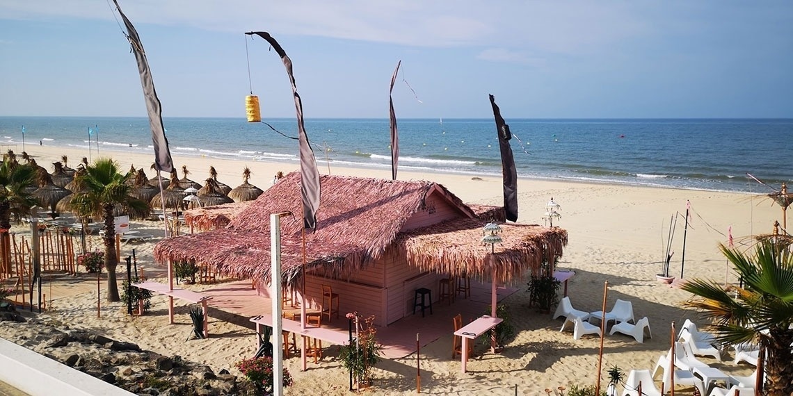 a thatched hut sits on a sandy beach near the ocean