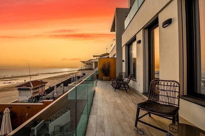 a balcony with a view of the ocean at sunset