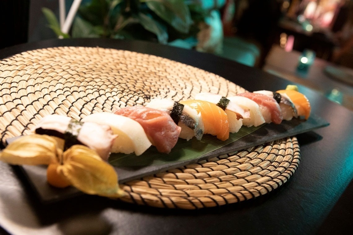 un plato de sushi está sobre una alfombra de mimbre