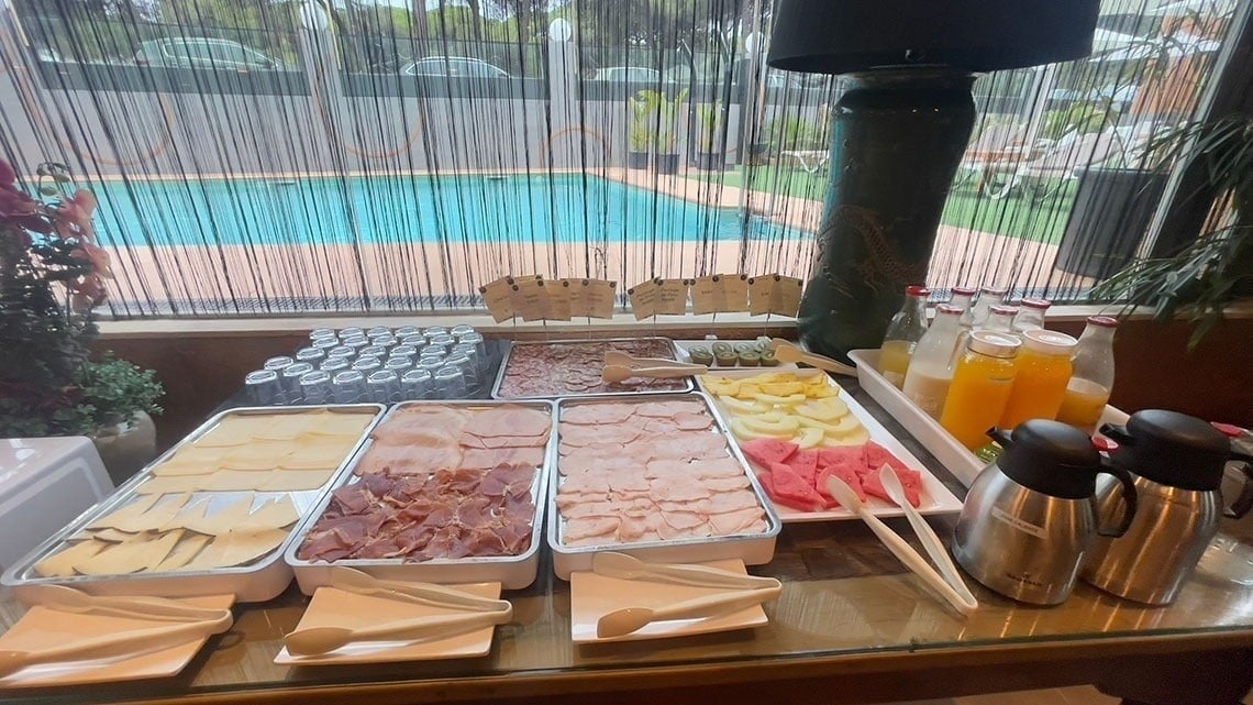 una mesa llena de comida y bebidas frente a una piscina