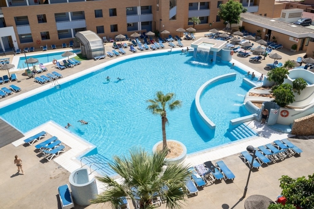 a large swimming pool surrounded by chairs and palm trees