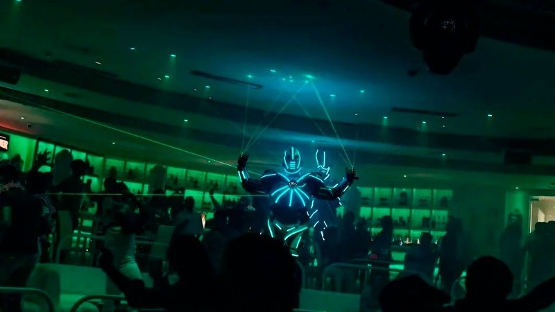 a group of people are dancing in a dark room with a glowing man in the middle