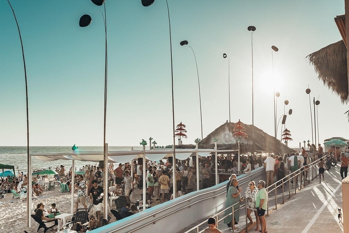 una multitud de personas se reúnen en la playa para una fiesta