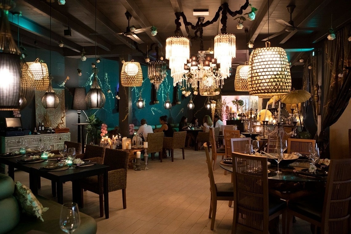 un restaurante lleno de mesas y sillas con lámparas colgando del techo