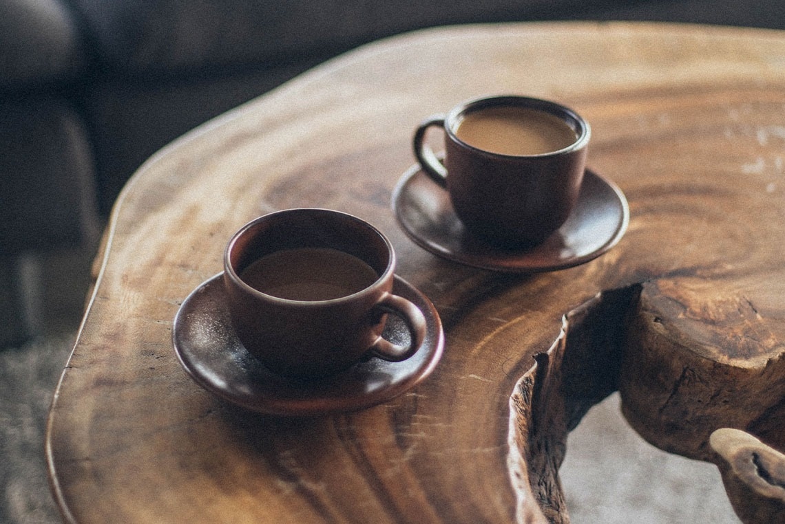 dos tazas de café están sobre una mesa de madera