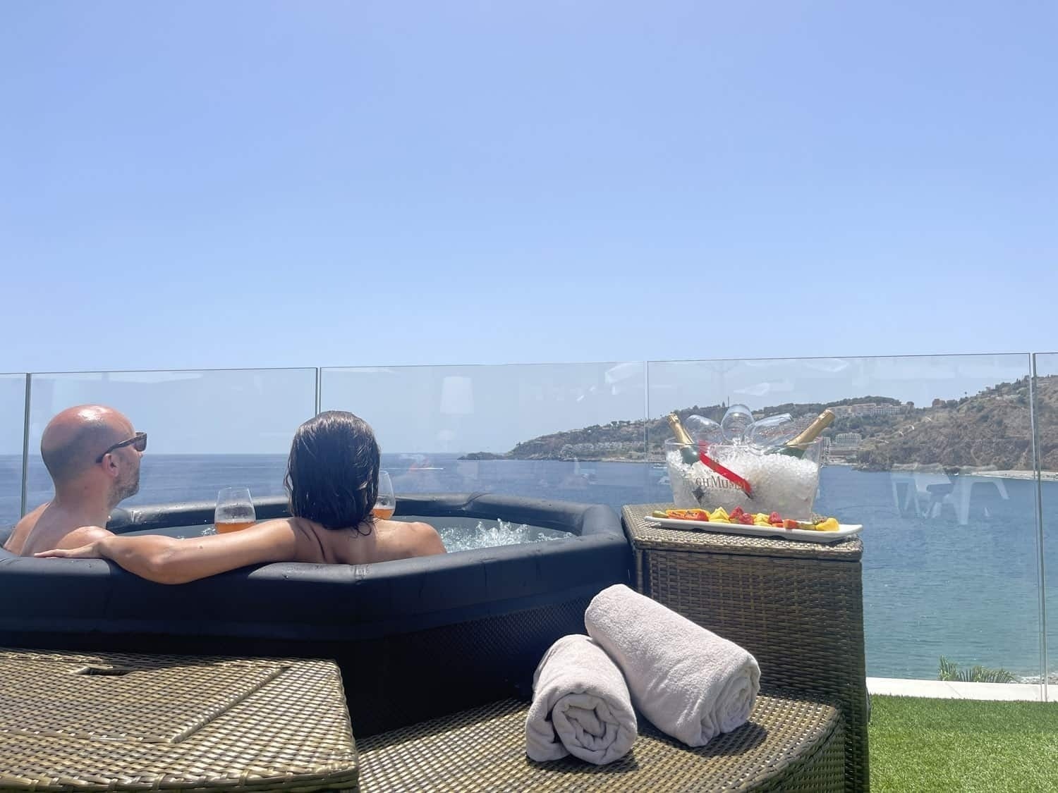 a man and a woman sit in a hot tub overlooking the ocean