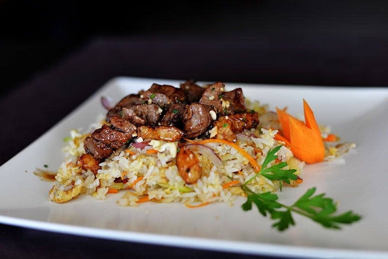 un plato blanco lleno de arroz y carne con zanahorias y perejil