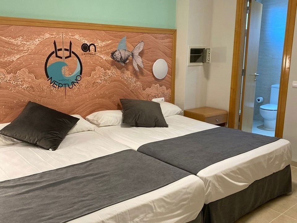 a hotel room with two beds and a headboard that says hotel neptune