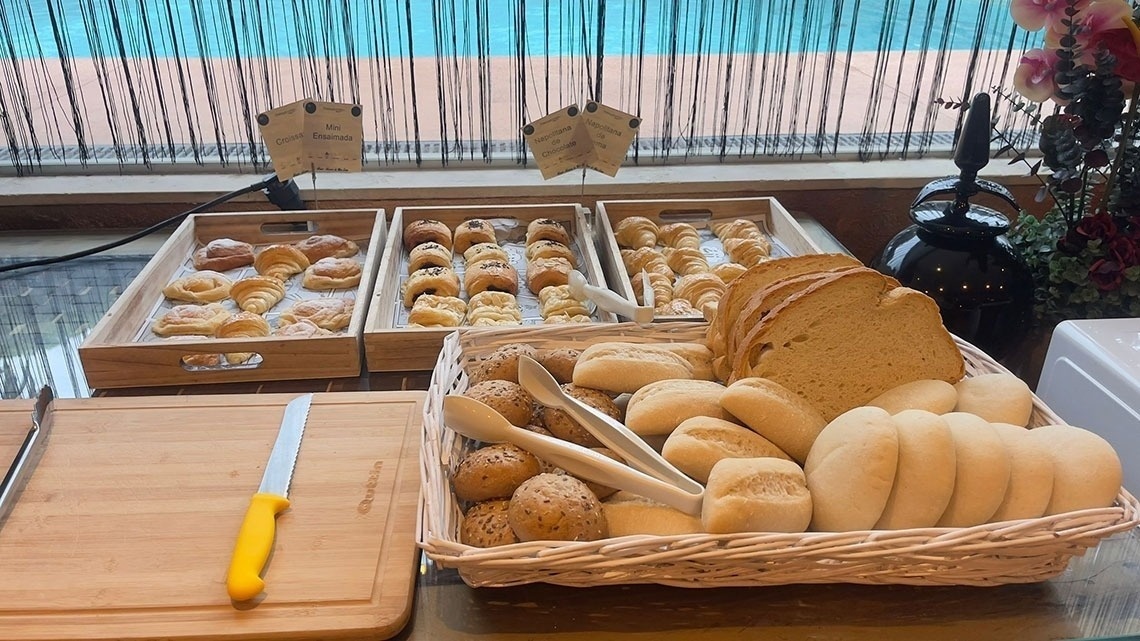a basket of bread sits on a table next to a cutting board