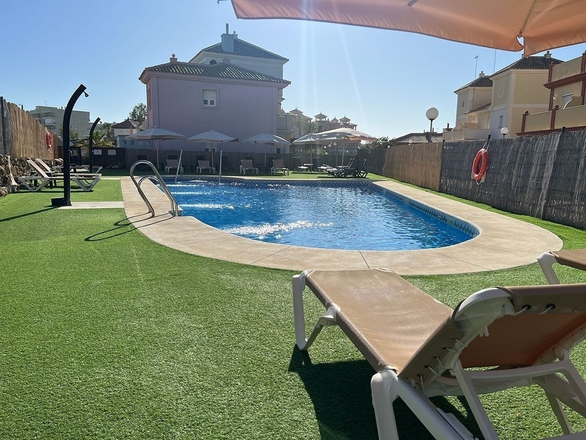una piscina rodeada de sillas y sombrillas en un día soleado