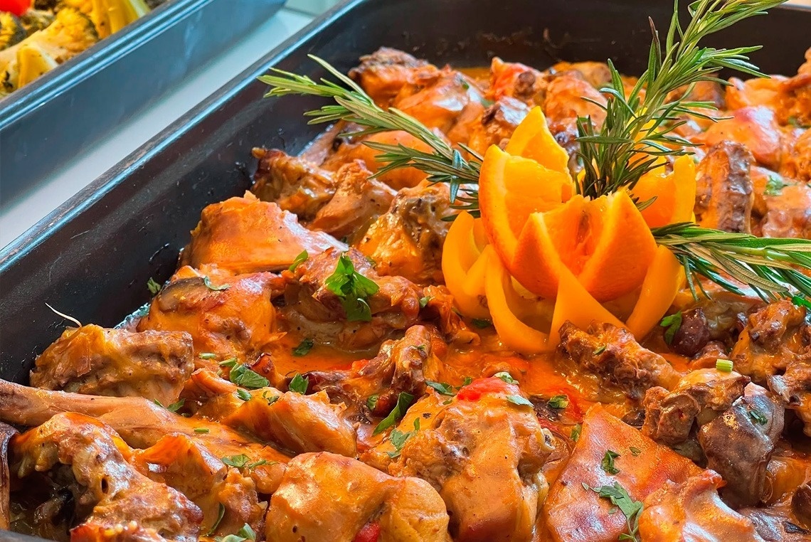 una bandeja de comida con carne y verduras y una flor de naranja