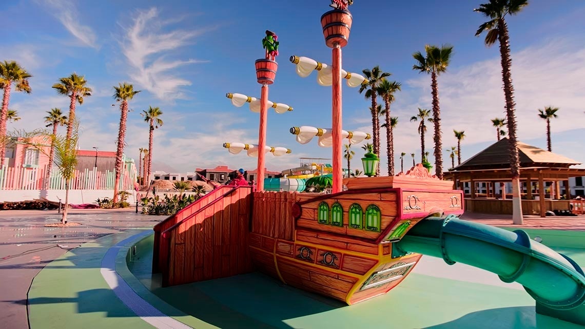 a pirate ship playground with a slide and palm trees in the background