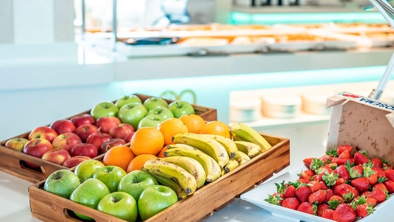 una bandeja de madera llena de manzanas , naranjas , plátanos y fresas