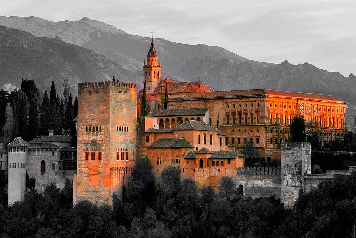 un gran edificio con una torre en la parte superior está rodeado de montañas