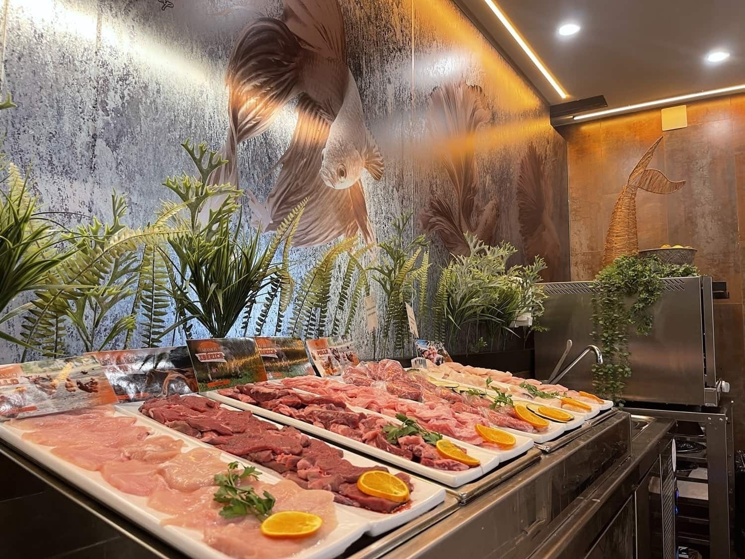 several trays of meat are lined up in front of a wall with a picture of a fish on it