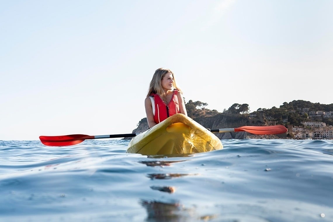 une femme dans un kayak jaune avec une pagaie rouge