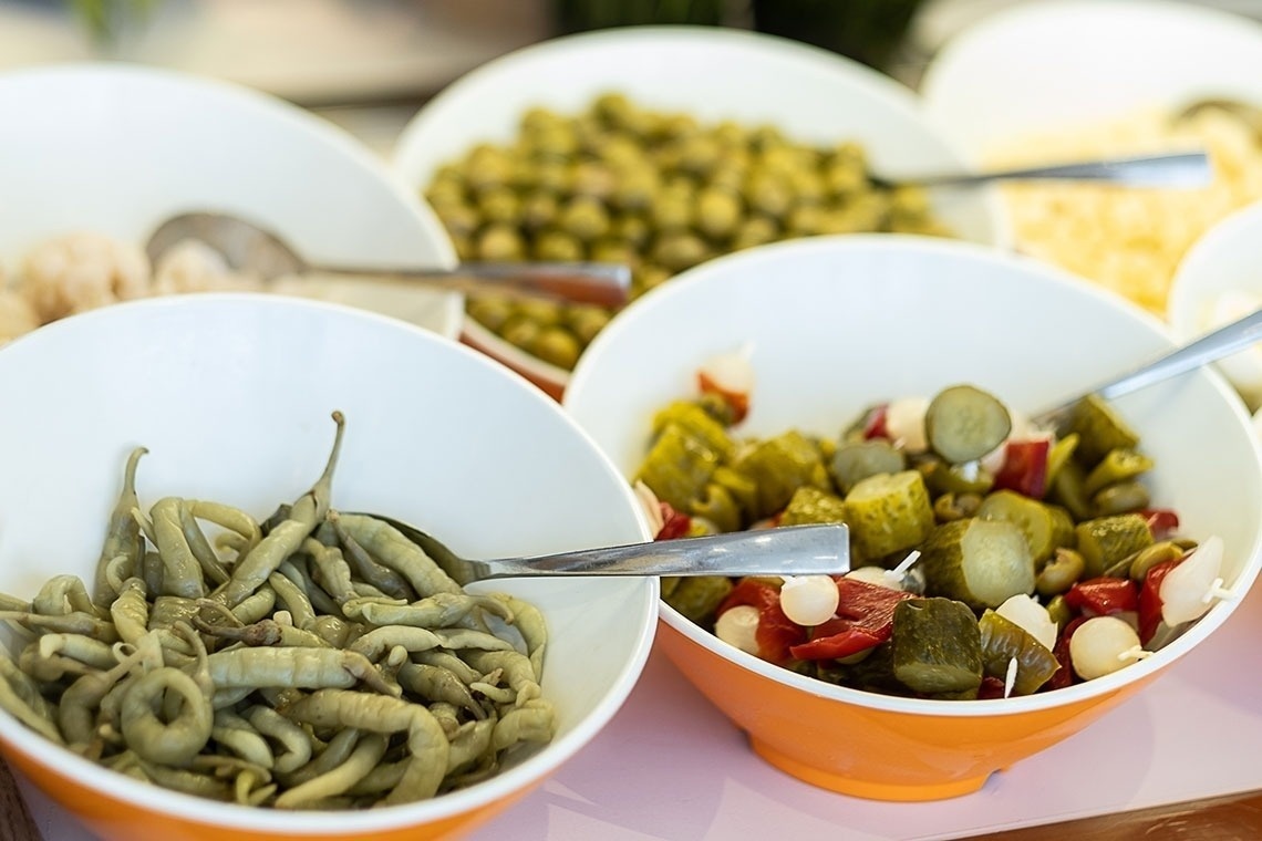 a bowl of green beans sits next to a bowl of pickles