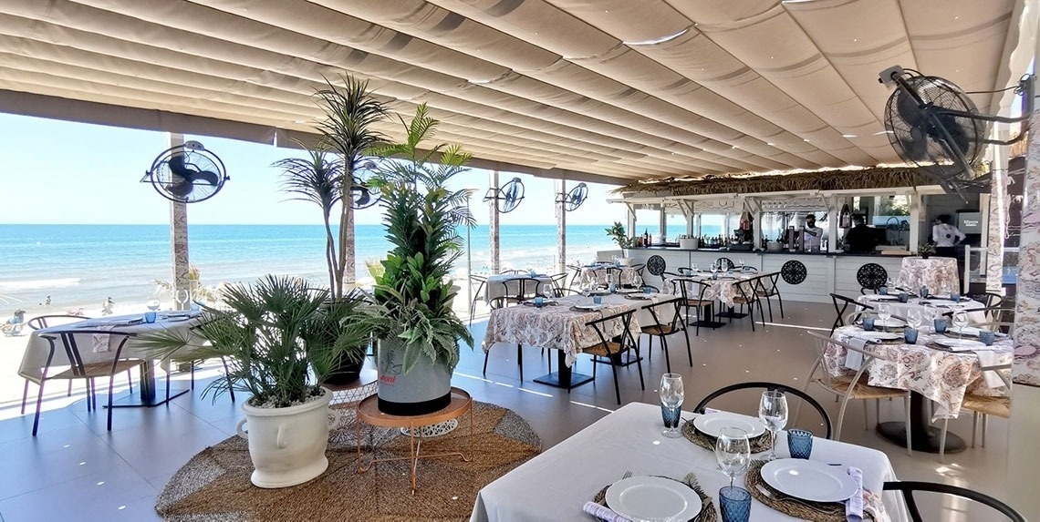 a restaurant with tables and chairs with a view of the ocean