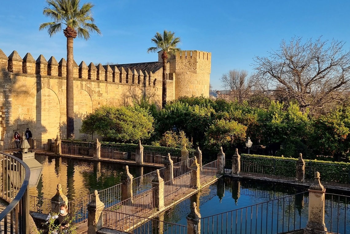 eine Brücke über einen Teich mit einem Turm im Hintergrund