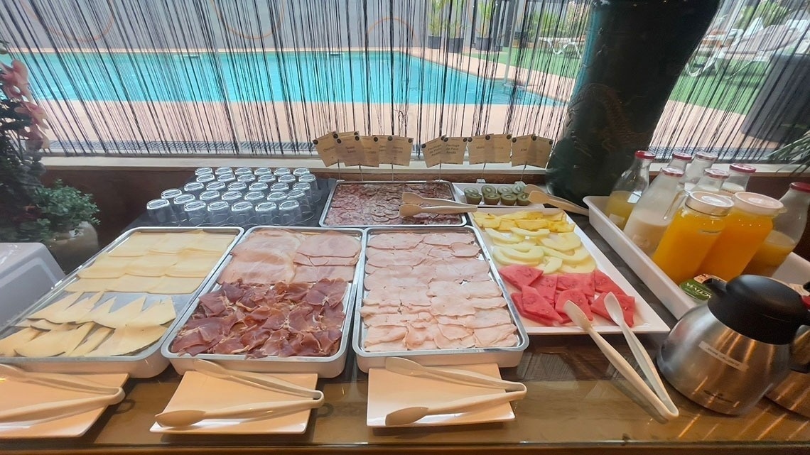 a variety of food and drinks on a table with a pool in the background
