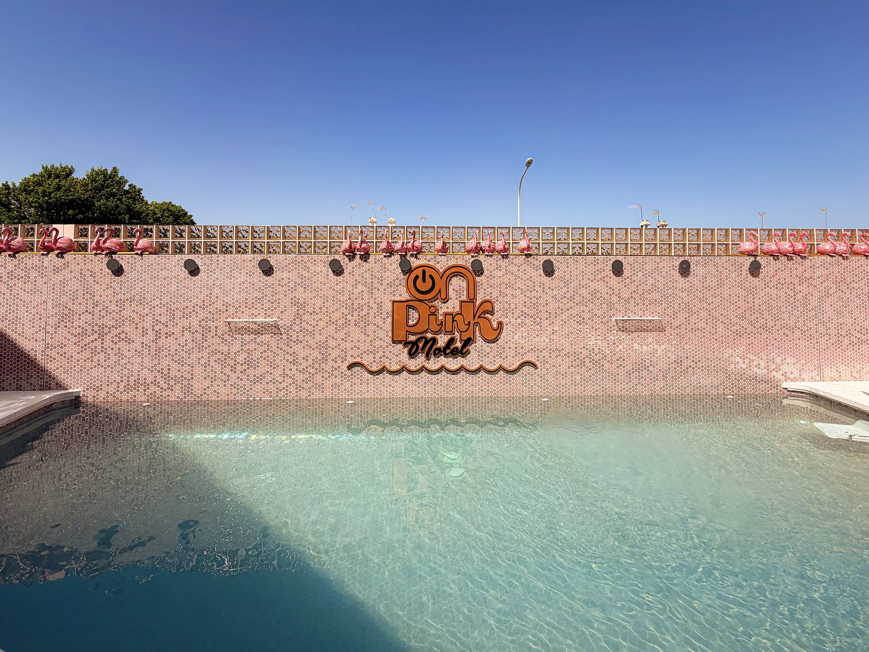 Einladender Pool vor der pinken Motelwand mit Flamingodekorationen. ON Pink Motel | Matalascañas