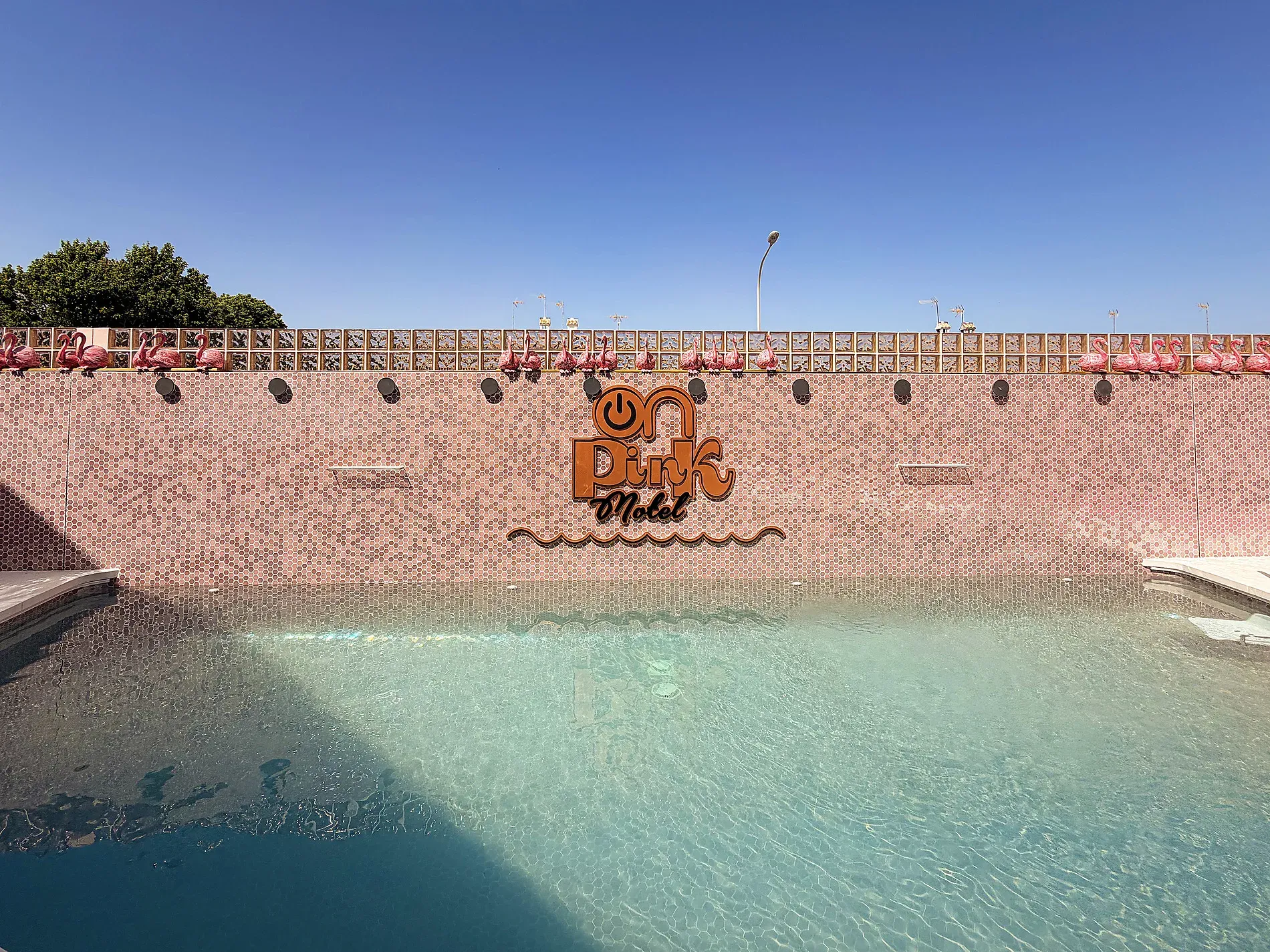 Einladender Pool vor der pinken Motelwand mit Flamingodekorationen. ON Pink Motel | Matalascañas