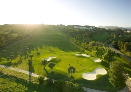 an aerial view of a golf course with the sun shining through the trees