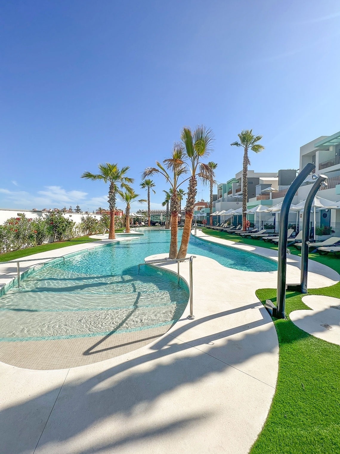 una gran piscina rodeada de palmeras en un resort