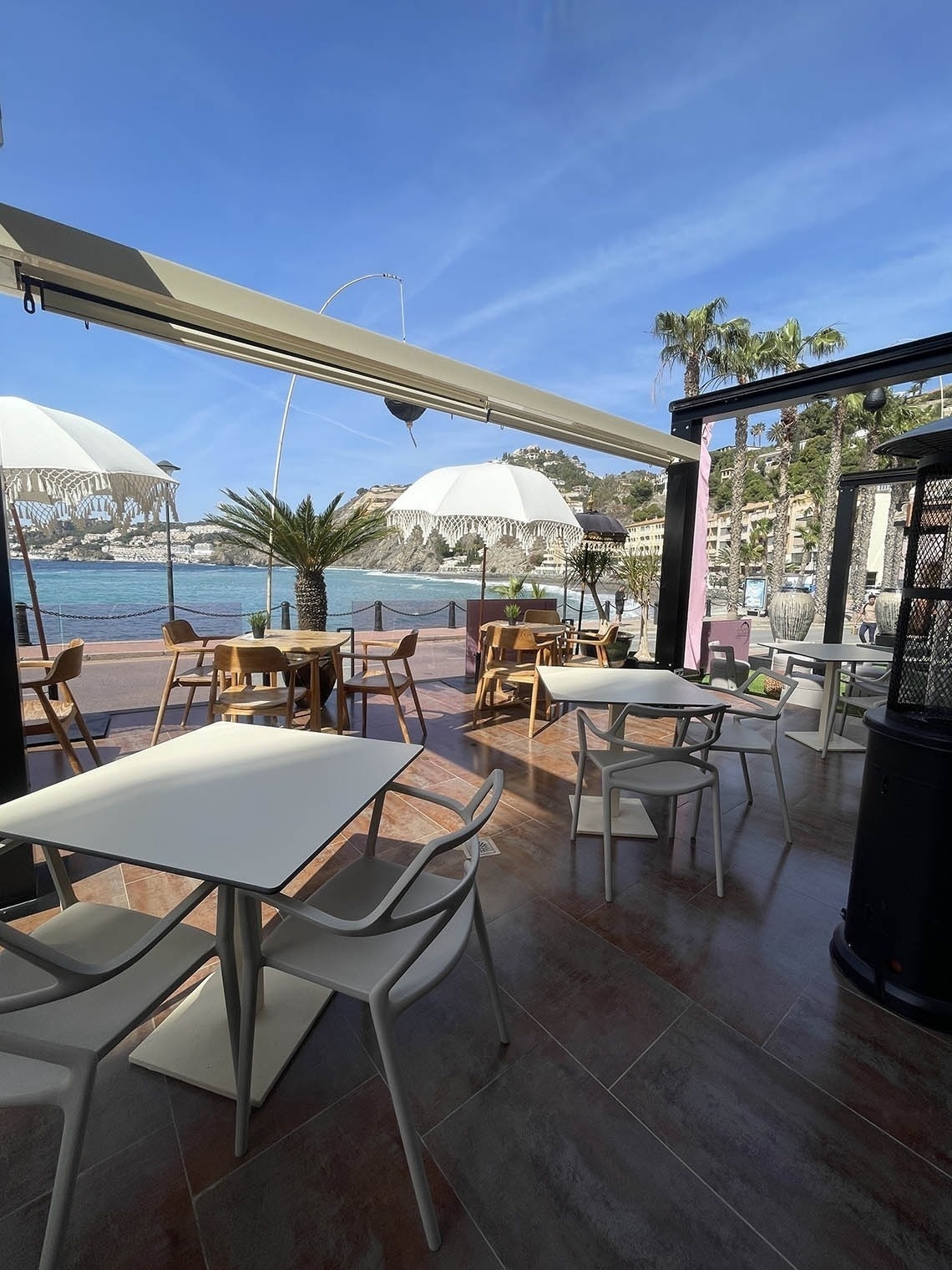 un restaurante con mesas y sillas al aire libre con vistas al océano