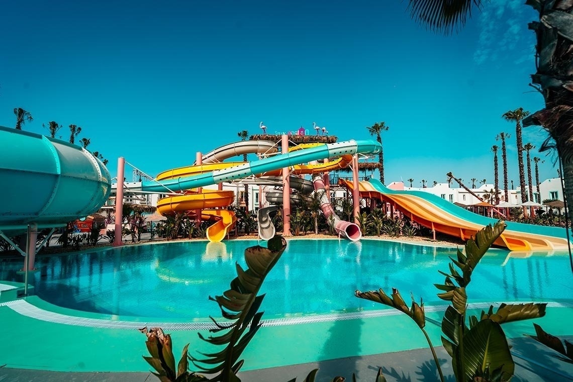 a large swimming pool surrounded by palm trees and umbrellas