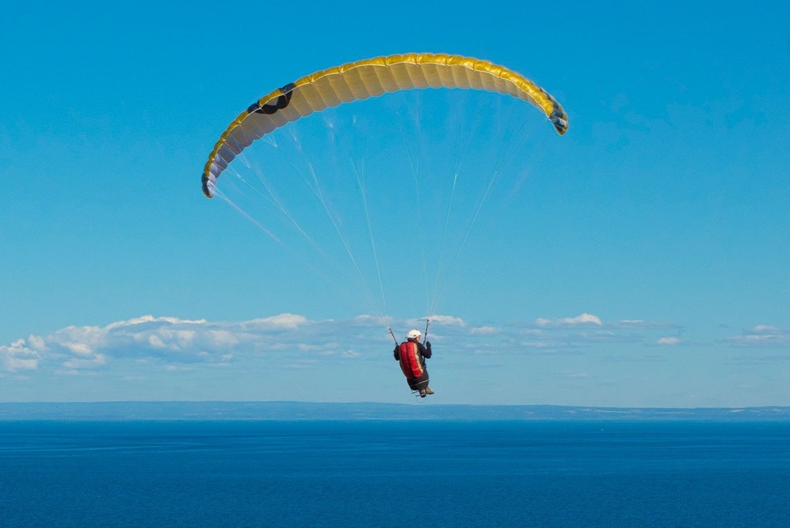 a person is flying a parachute over the ocean