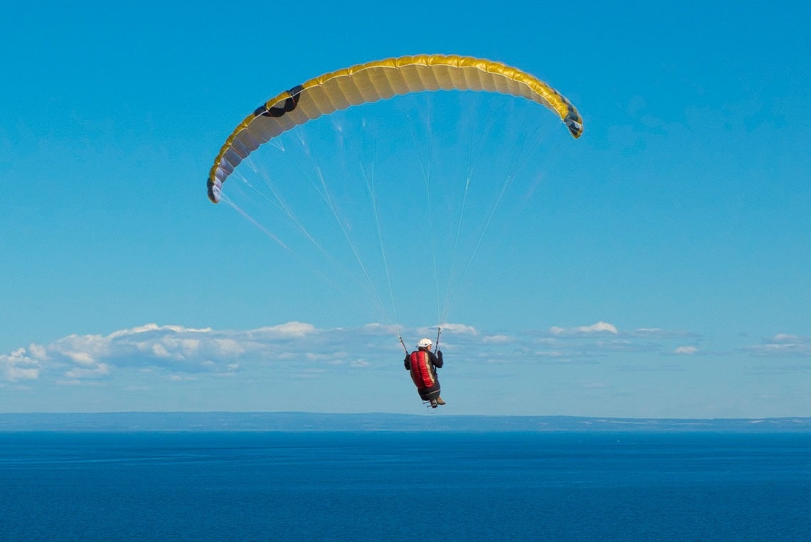 ein Mann fliegt mit einem Gleitschirm über das Meer