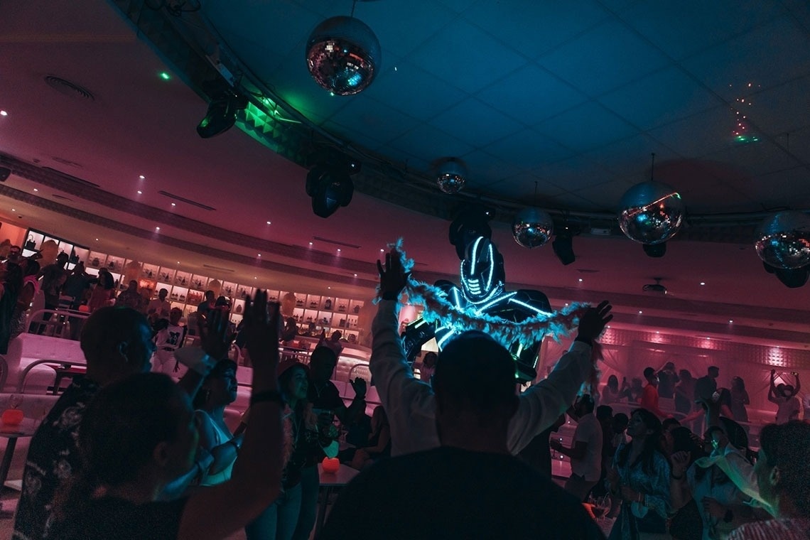 un grupo de personas bailan en una discoteca con un pulpo en el fondo