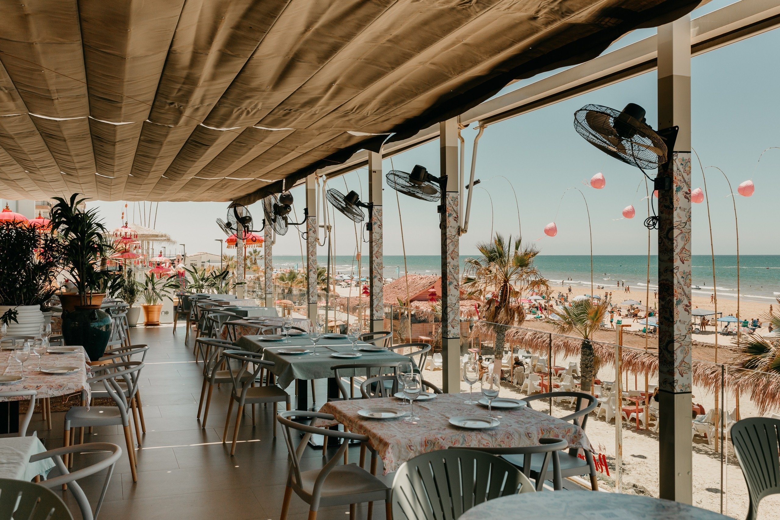 un restaurante lleno de mesas y sillas con una vista al mar