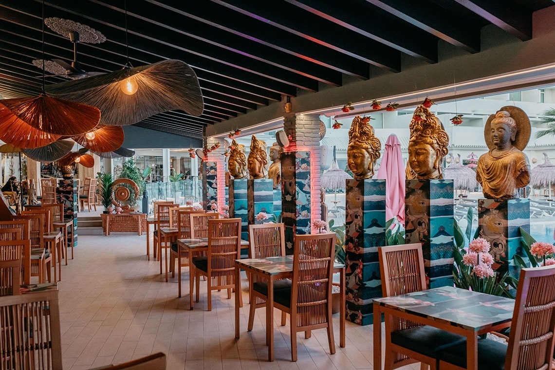 une salle à manger avec des tables et des chaises et des lampes suspendues au plafond