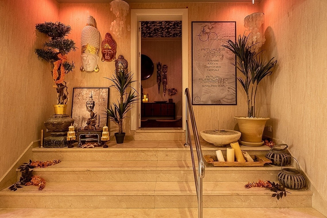 una escalera que conduce a una habitación decorada con estatuas de buda y plantas
