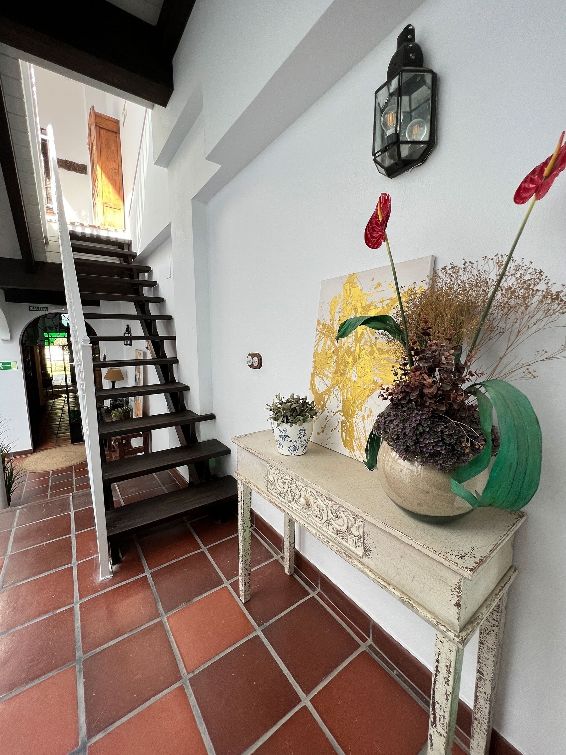 a table with a vase of flowers on it in front of a staircase