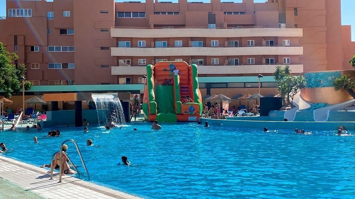 una piscina llena de gente y un tobogán inflable