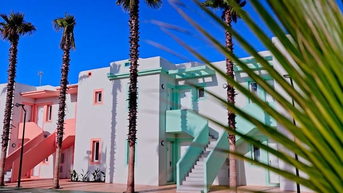 un edificio blanco con escaleras verdes está rodeado de palmeras