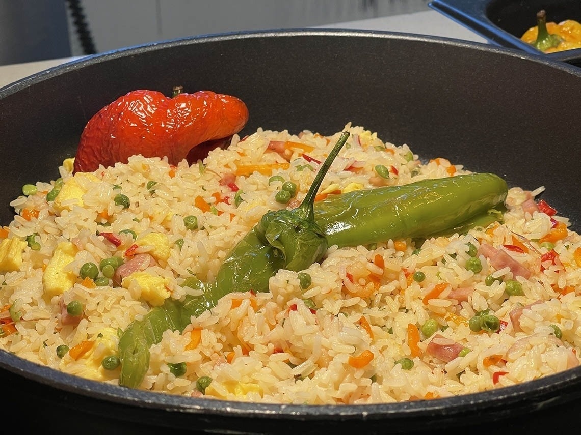 a pan filled with rice and vegetables with a green pepper on top
