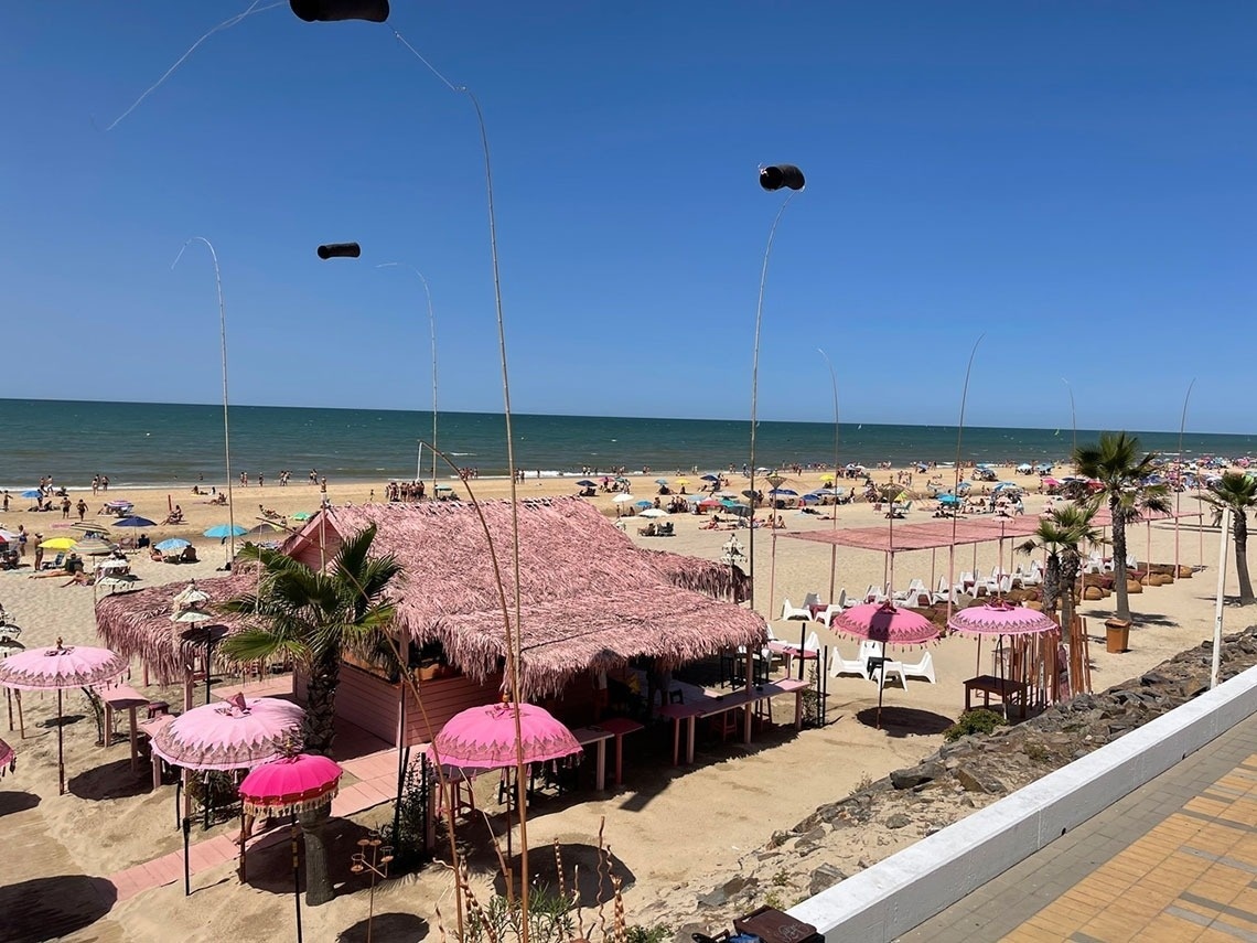 a beach with pink umbrellas and a pink hut