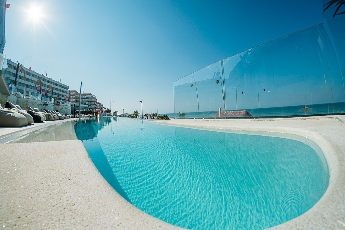 una piscina infinita con una barandilla de vidrio que mira al océano