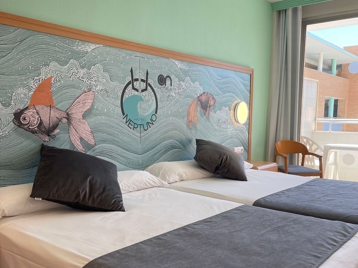 a hotel room with two beds and a mural that says neptuno
