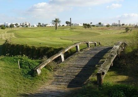 a wooden bridge over a river leading to a golf course .