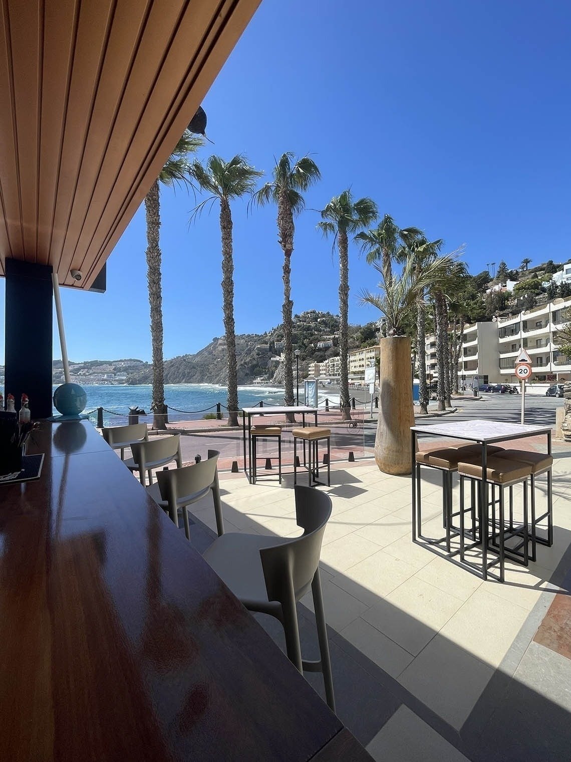 a view of the ocean from a restaurant with tables and chairs