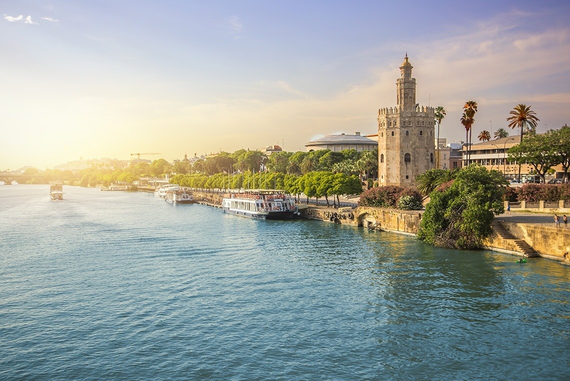 un río con barcos y una torre en el fondo