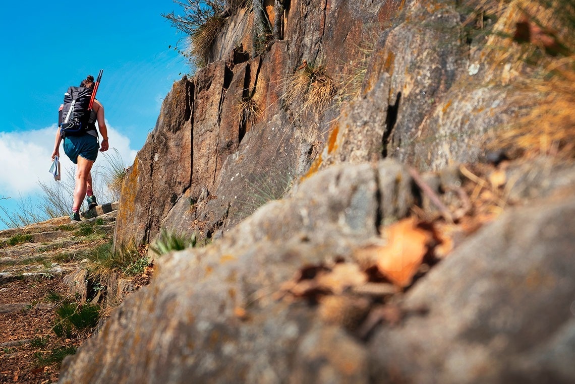 a person with a backpack is walking up a rocky hillside