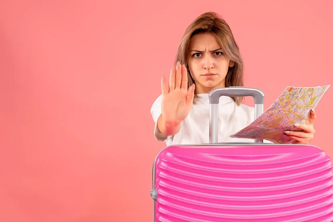 On Hotels: ON Corporativa. Mujer joven con maleta rosa y mapa, gesto de stop.