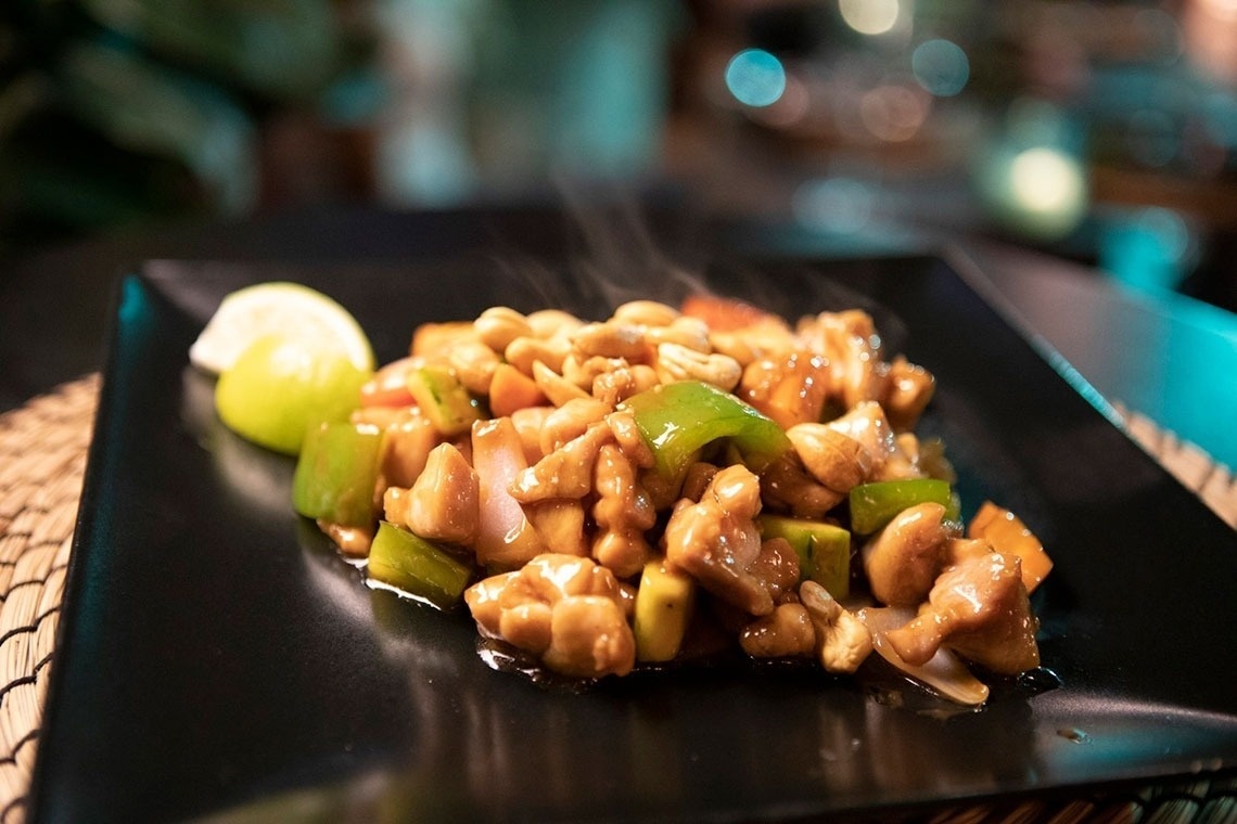 a black plate topped with chicken and green peppers